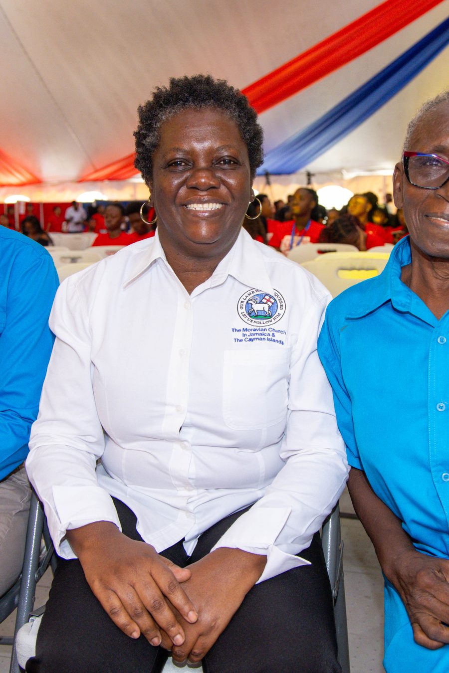 Three members of staff seated under the University Tent