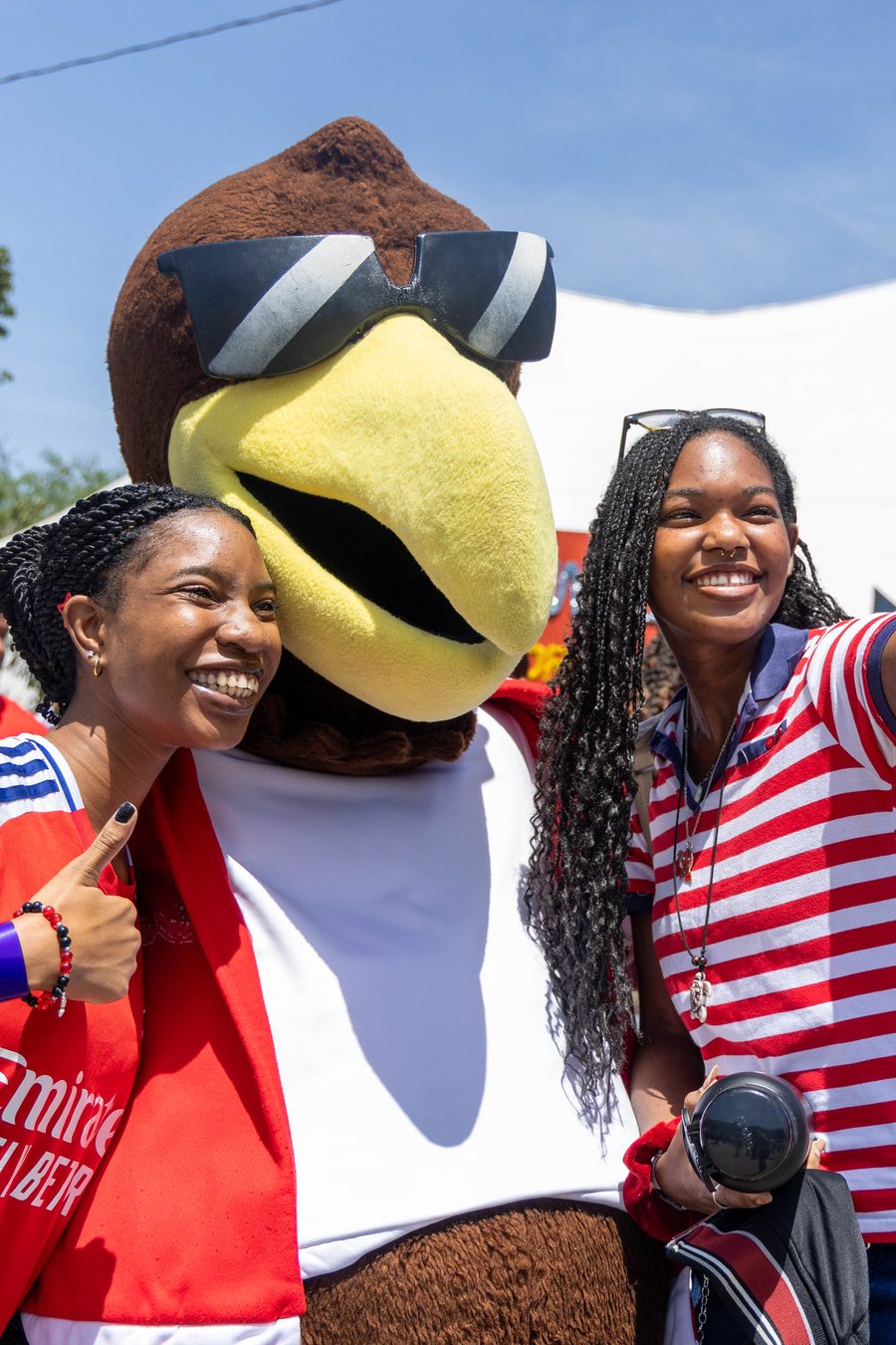 Two students taking a selfie with the Pelican mascot