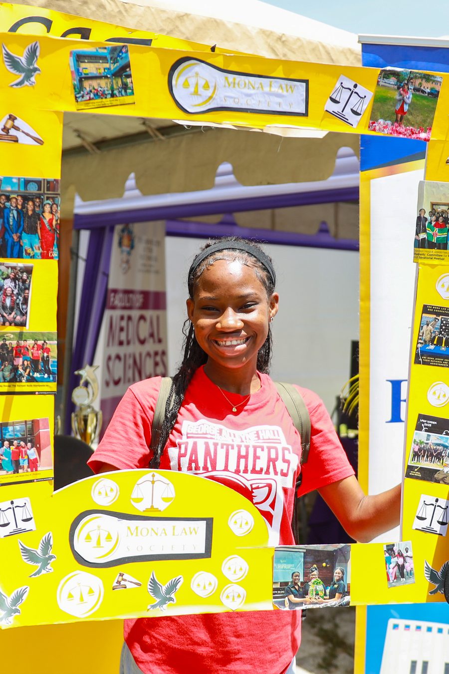 A student holding a Panthers hall sign at an Expo Village booth
