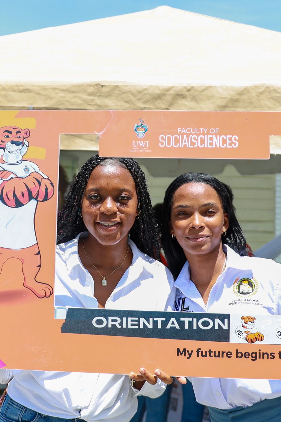 Two students posing in an Orientation photo frame at the Social Sciences booth