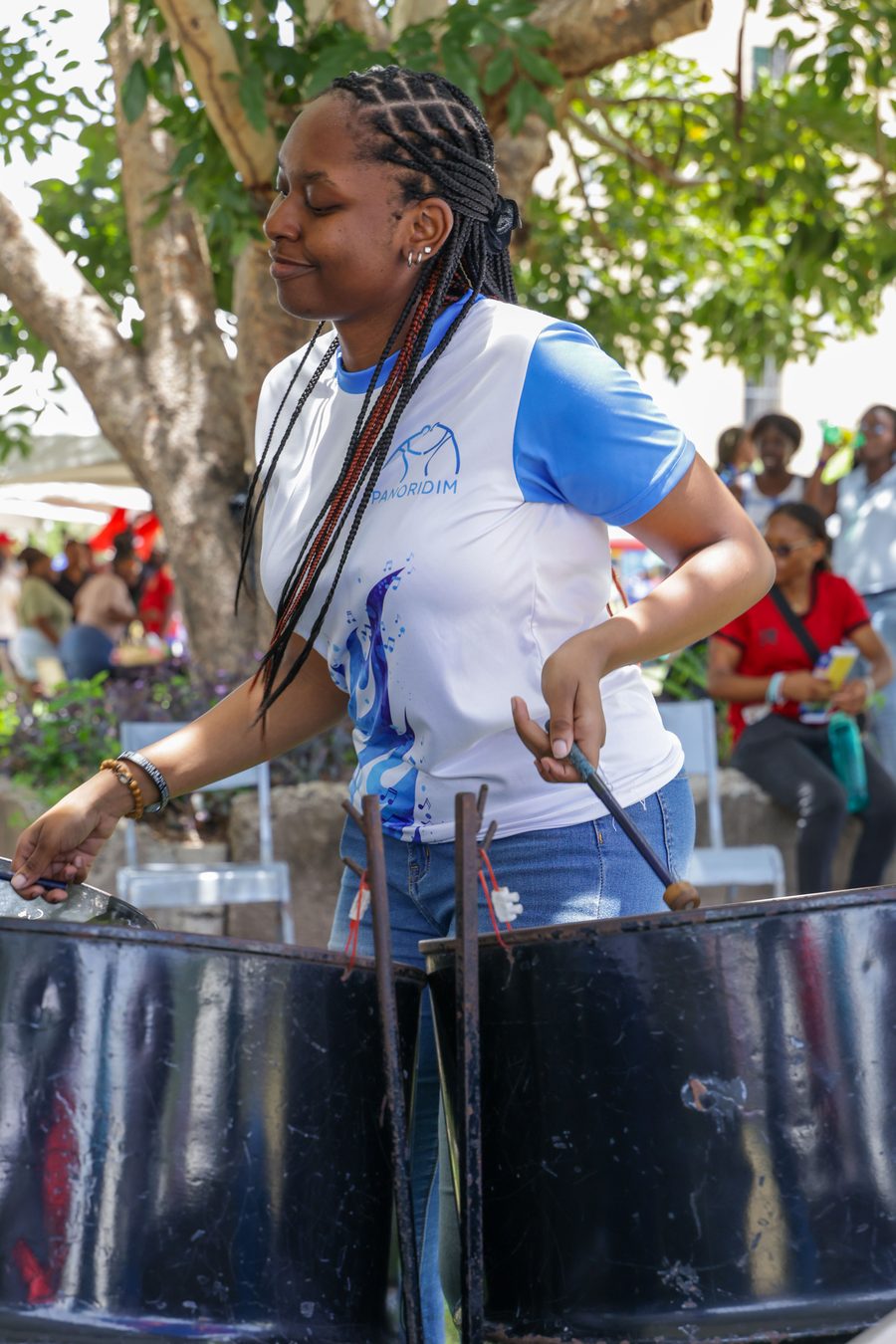 A student playing steel pan under the trees